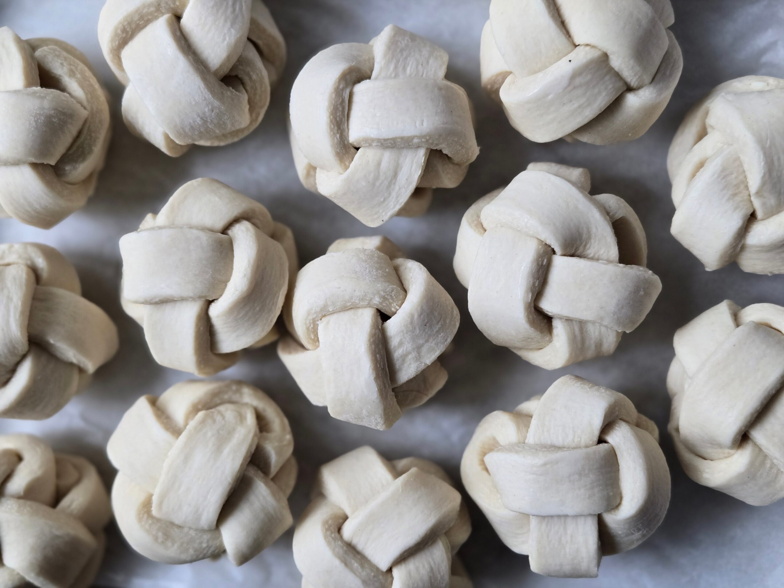 Close-up of raw, knotted dough pieces arranged on a surface.