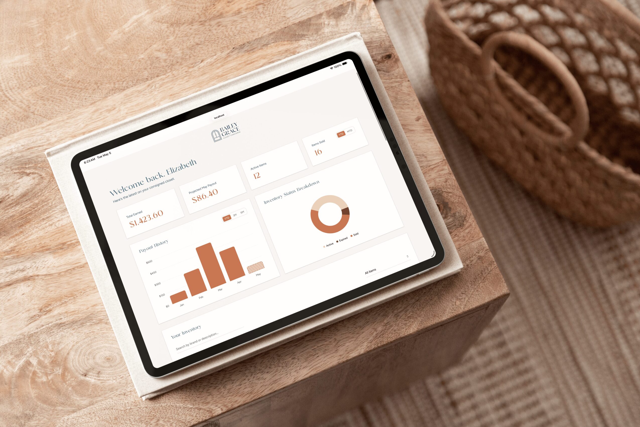 Tablet displaying a financial dashboard with bar and pie charts on a wooden surface, next to a woven basket.