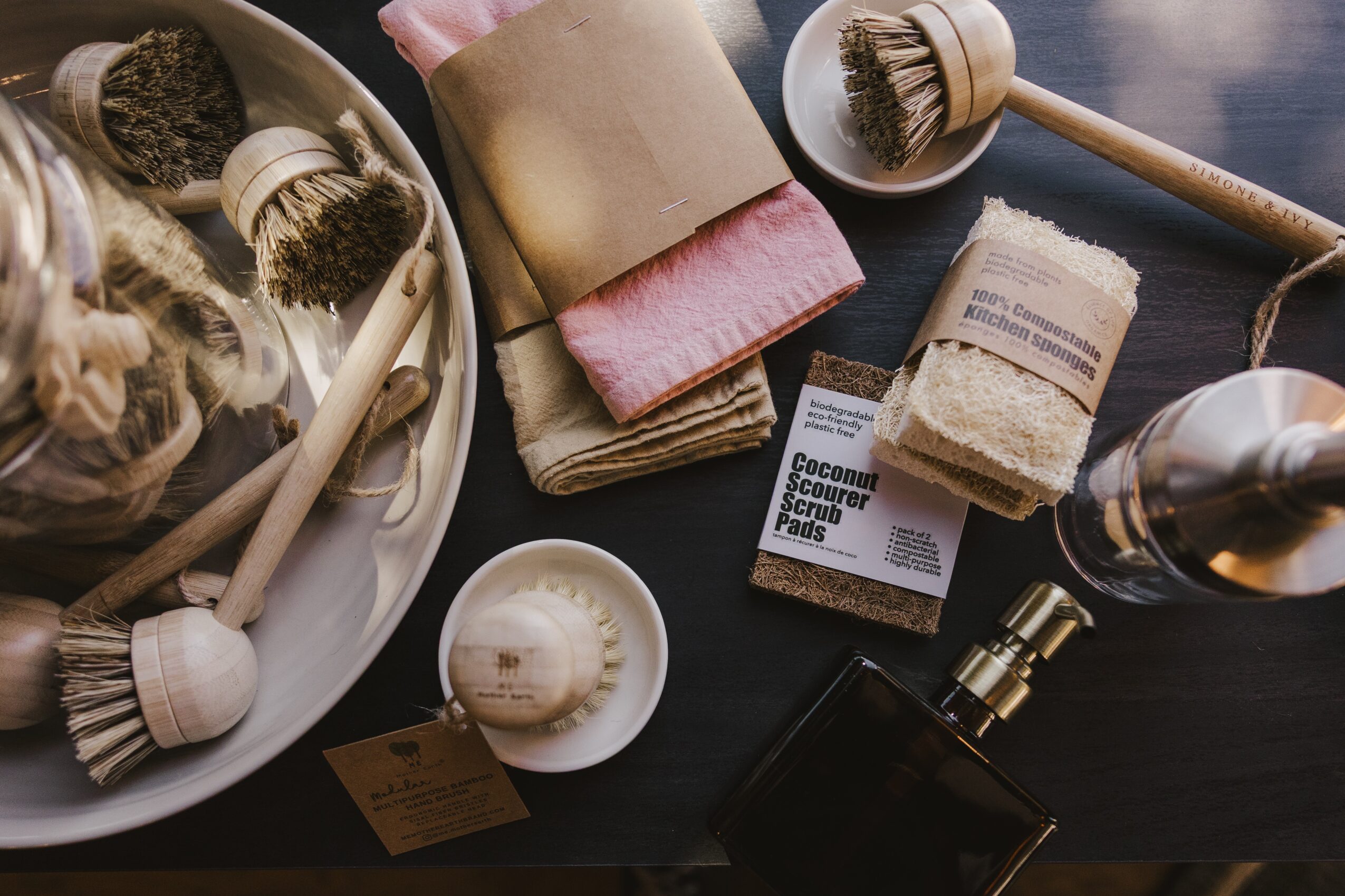 Collection of bath and skincare items including brushes, soap, sponge, and a bottle on a dark surface.