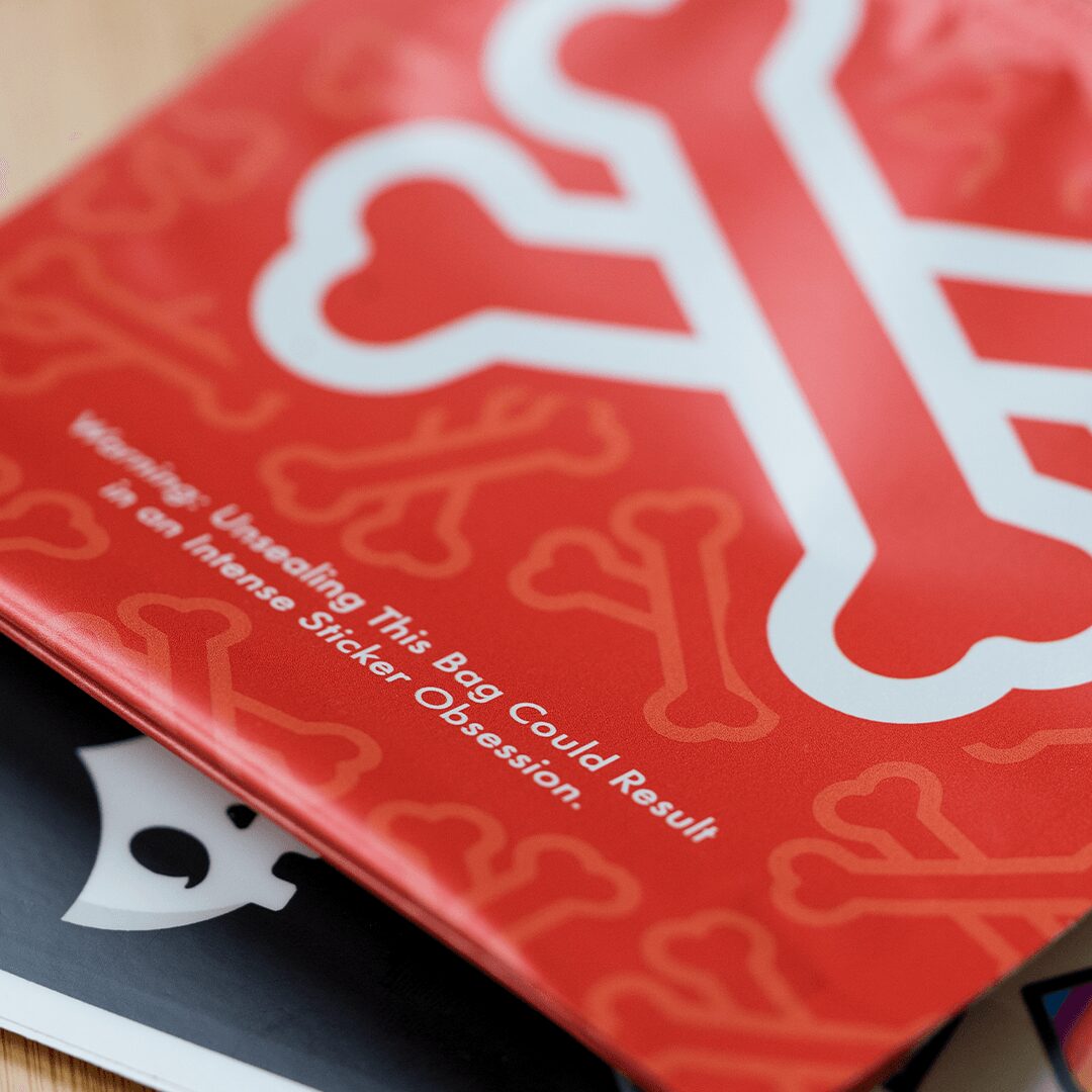 Red bag with white stylized snowflake design and text warning about sticker removal, close-up view.
