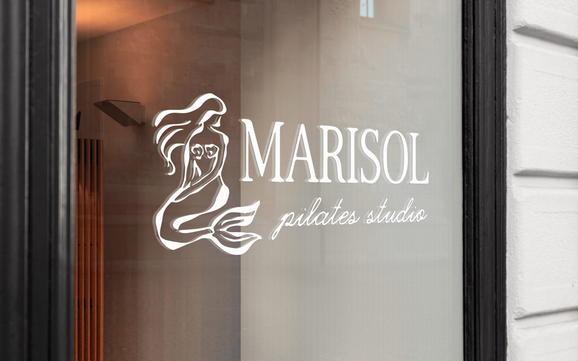 Glass window with white logo of a mermaid and text 'MARISOL pilates studio'.