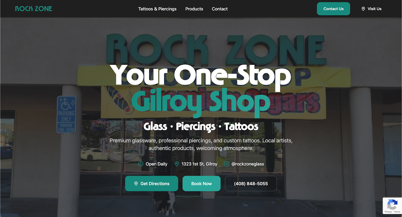 Storefront with sign reading 'Rock Zone Gilroy Shop' offering tattoos, piercings, and glass art, with a parking lot in front.