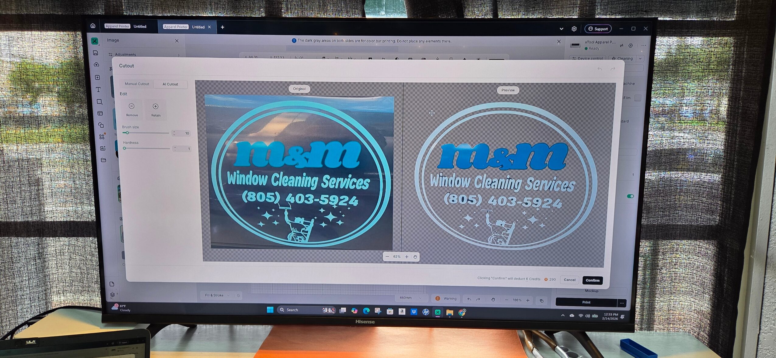 Computer monitor displaying a logo design for 'Window Cleaning Services' with contact number, on a desk with a window in the background.