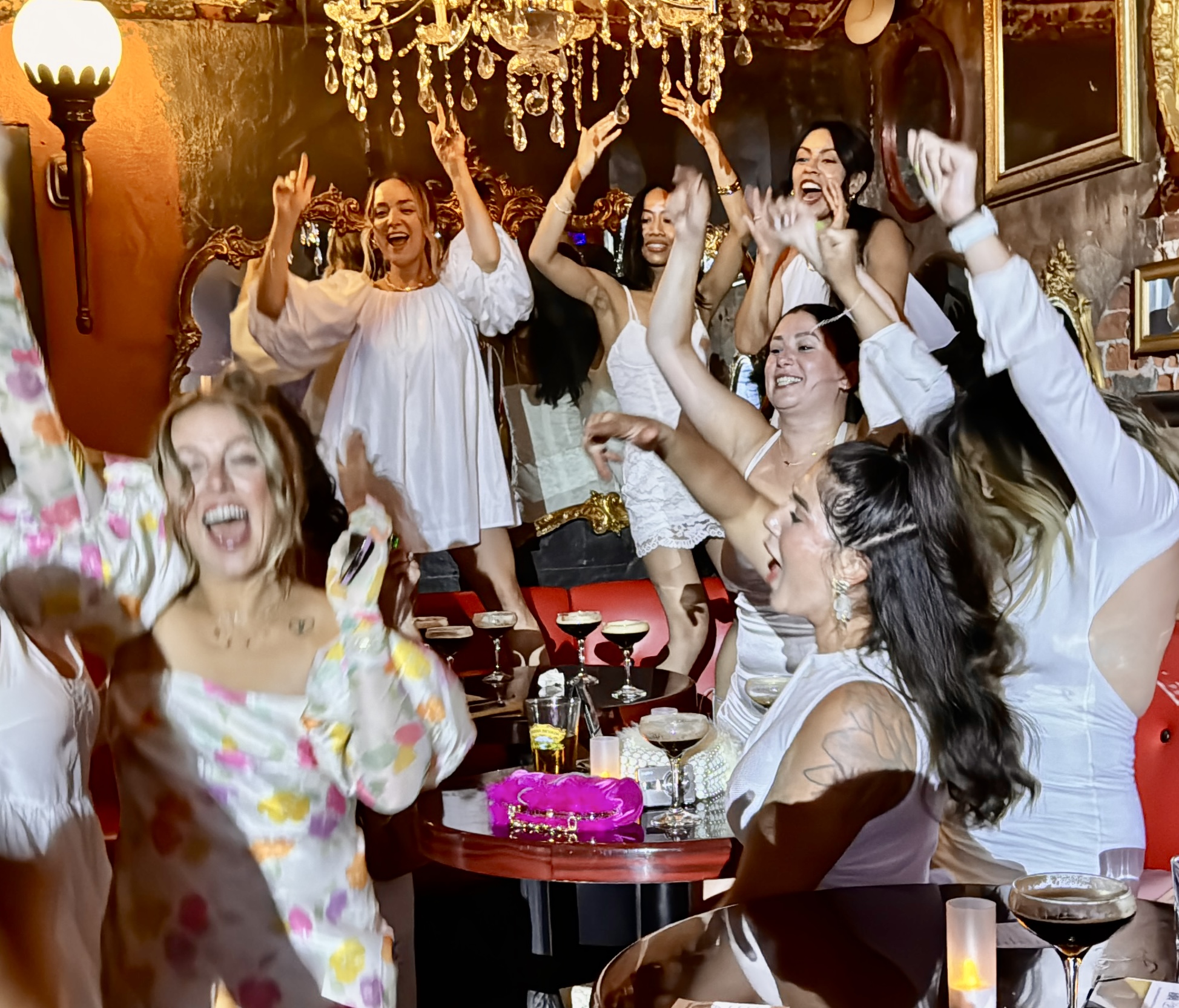 Group of women celebrating with a cake, dancing, and smiling in a decorated room.