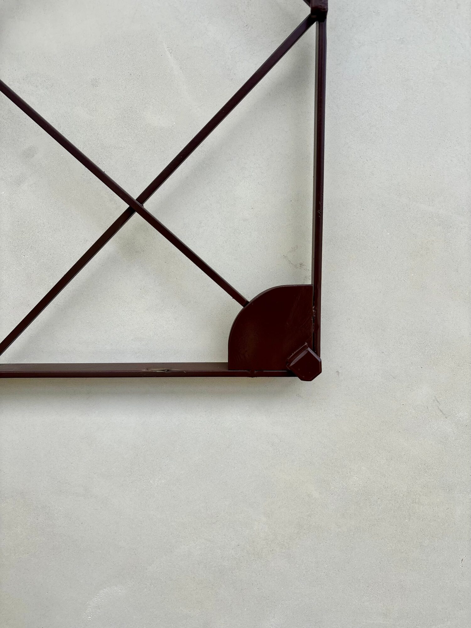 Corner of a metal frame with diagonal supports on a light-colored surface.