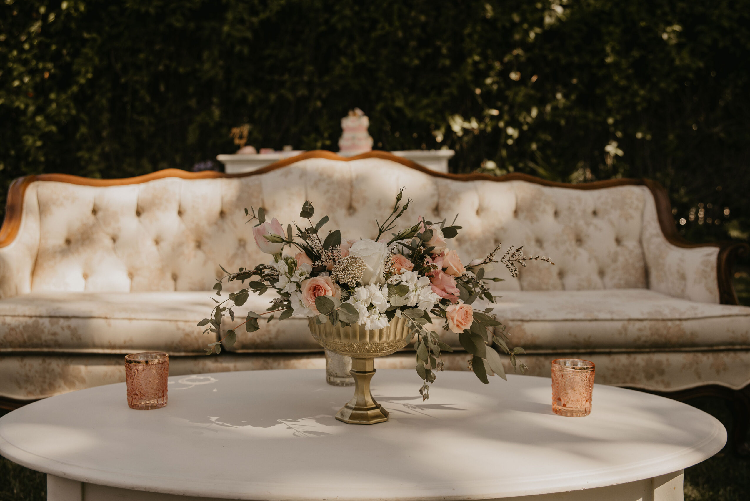Upright vintage sofa with floral centerpiece and two candles on a table in front.
