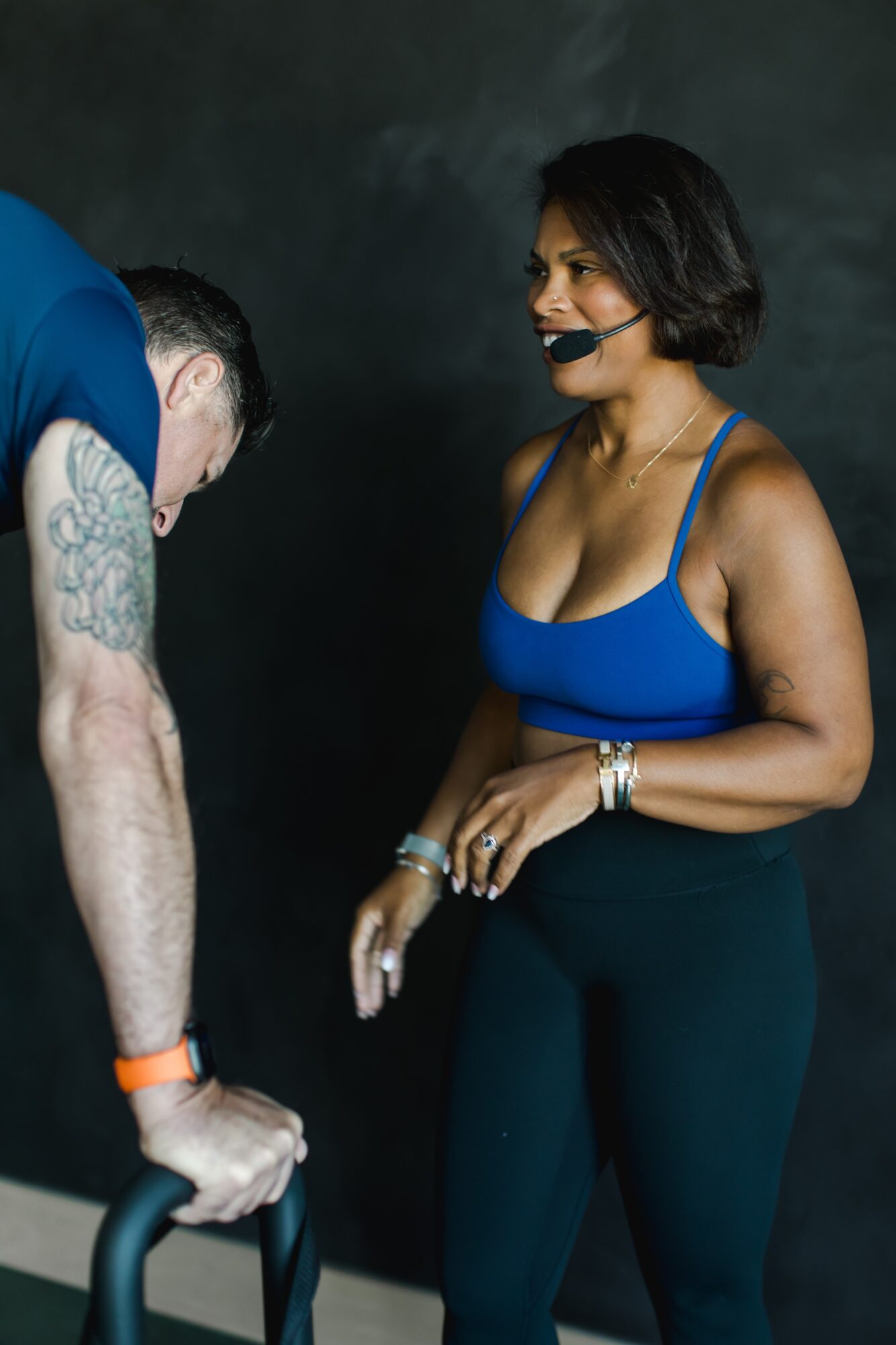 Two women engaged in conversation, one with short dark hair and a blue top, the other with tattoos and a black top.