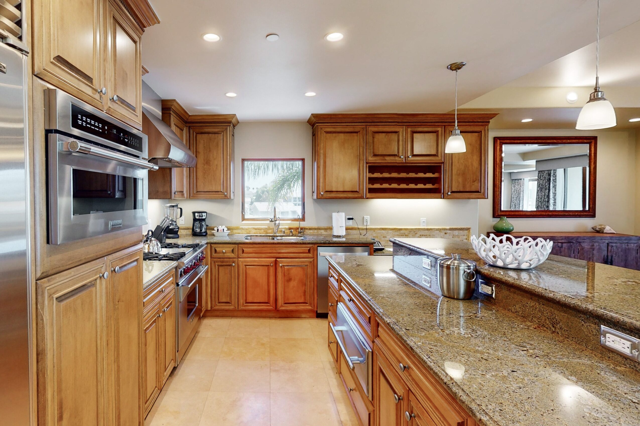 Kitchen with wooden cabinets, granite countertops, and stainless steel appliances, including a microwave and oven, with a window above the sink.
