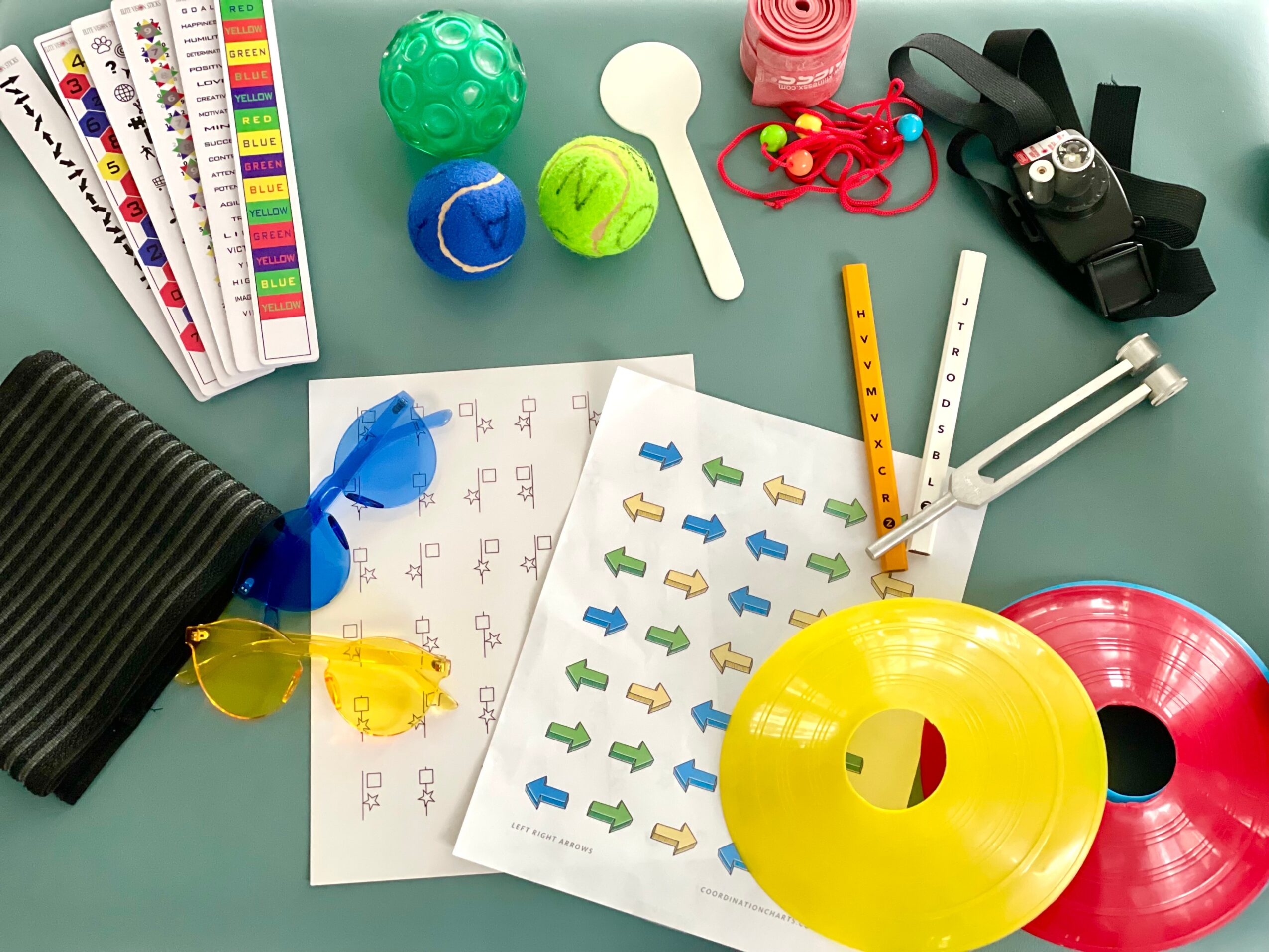 Various colorful toys, papers, and accessories on a light green surface, including balls, a flashlight, and a yellow ring.