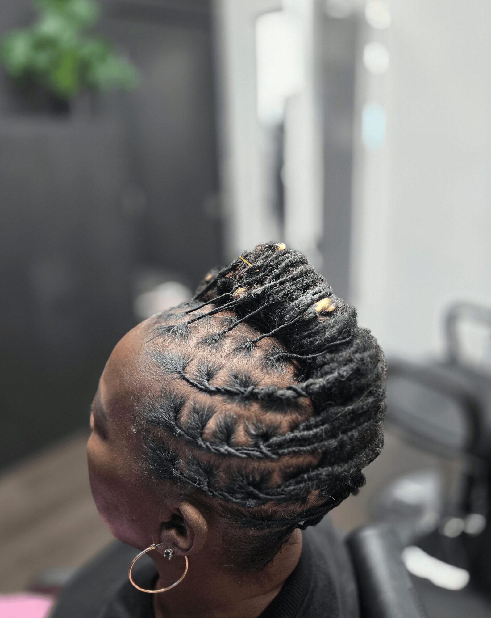 Side view of a woman with neatly styled braided hair, wearing a hoop earring, in a salon setting.
