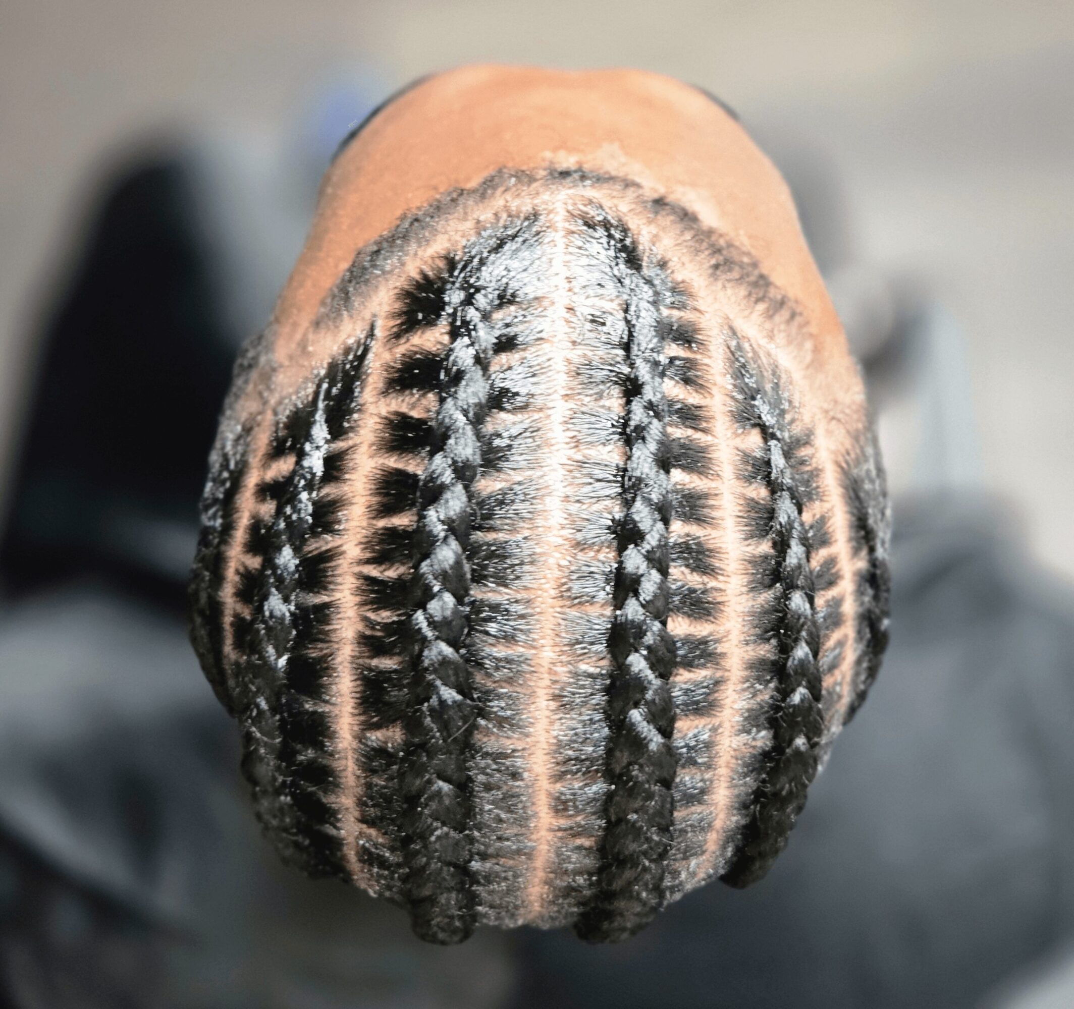 Top view of a person's head with neatly braided hair, showing intricate cornrows pattern.