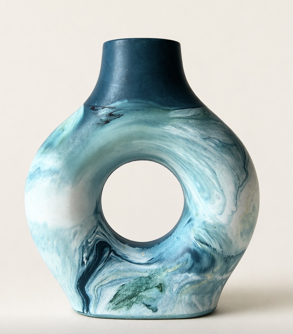 Ceramic vase with a circular hole in the center, blue and white marbled pattern, on a plain background.