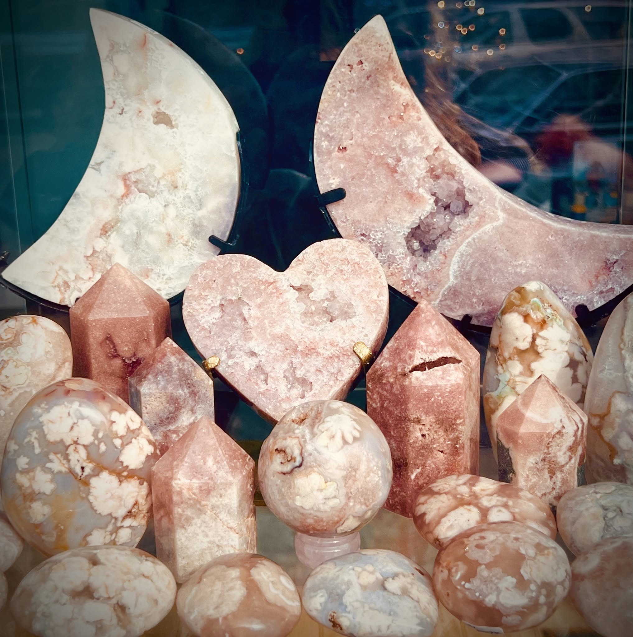 Display of pink and white moon-shaped and heart-shaped stones with various rounded and pointed stones in front.