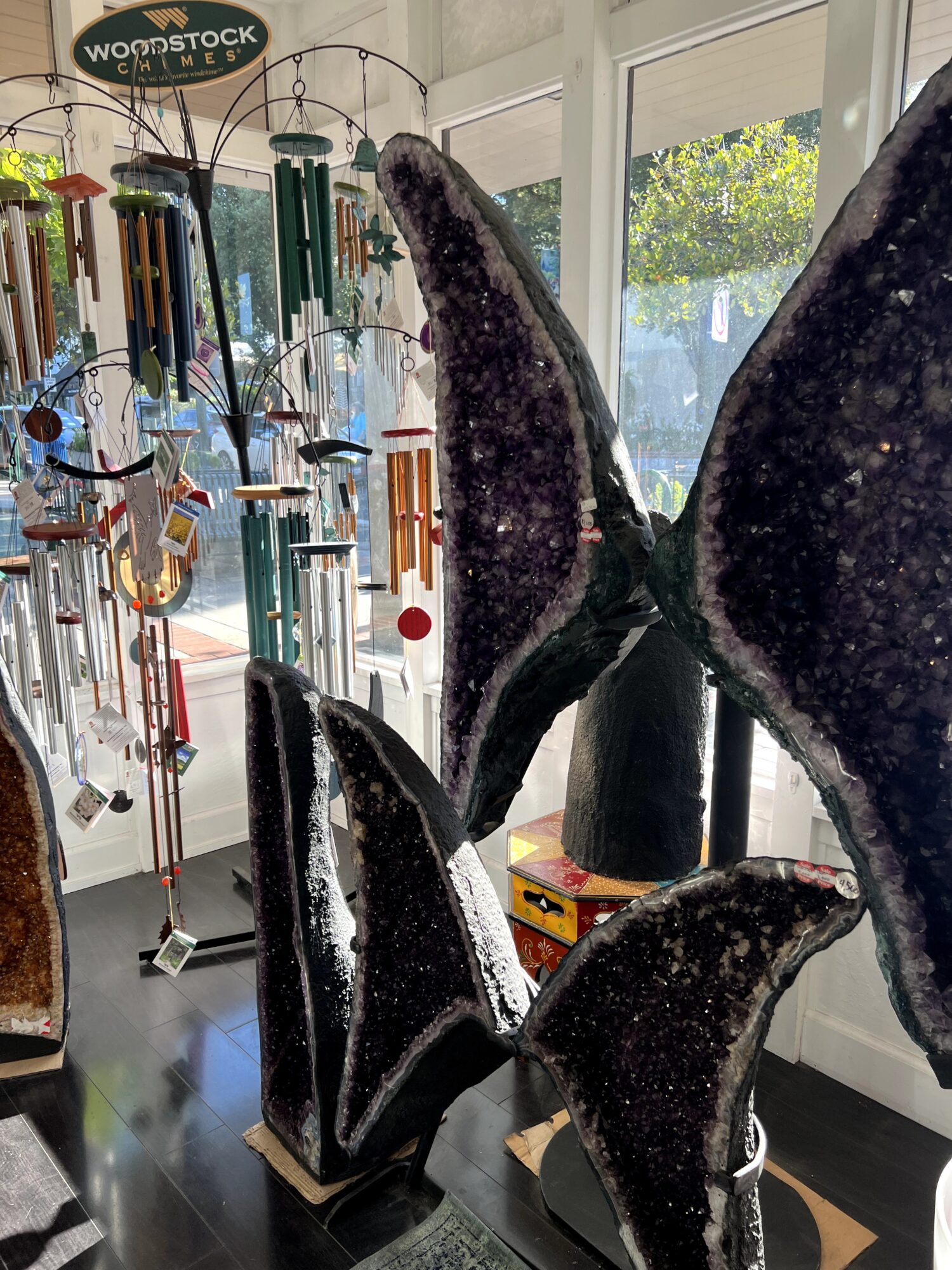 Indoor display of large whale sculptures with a window and wind chimes in the background.