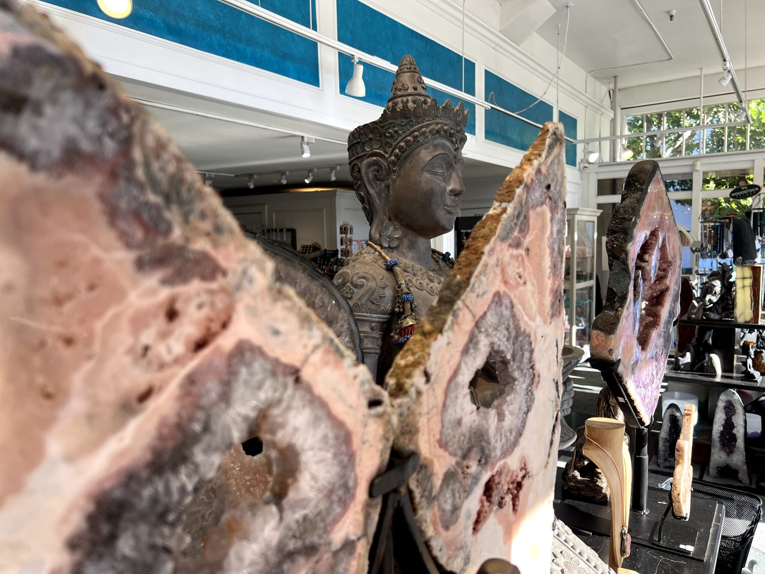 Statue of a person with an ornate headdress, surrounded by large geode slices in an indoor space.
