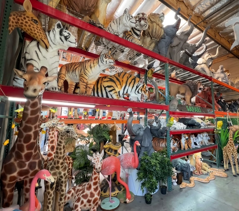 Shelves display various animal figurines including tigers, giraffes, flamingos, and elephants with plants and decorations.