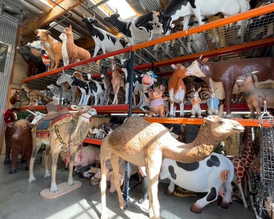 Shelves filled with various animal figurines including cows, camels, and other farm animals in a store.