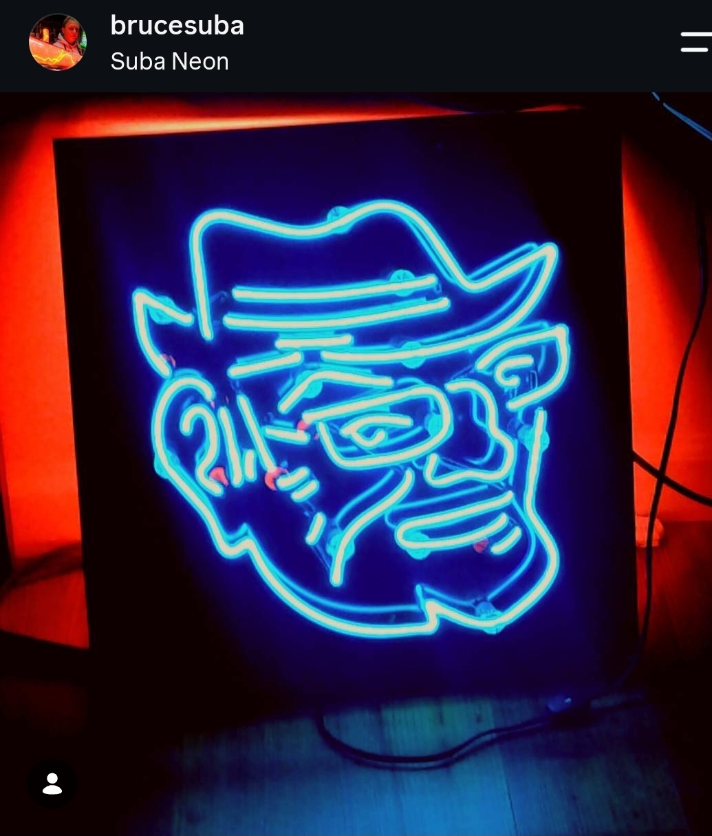Bright blue neon outline of a face with a hat, glasses, and beard, against a dark background.