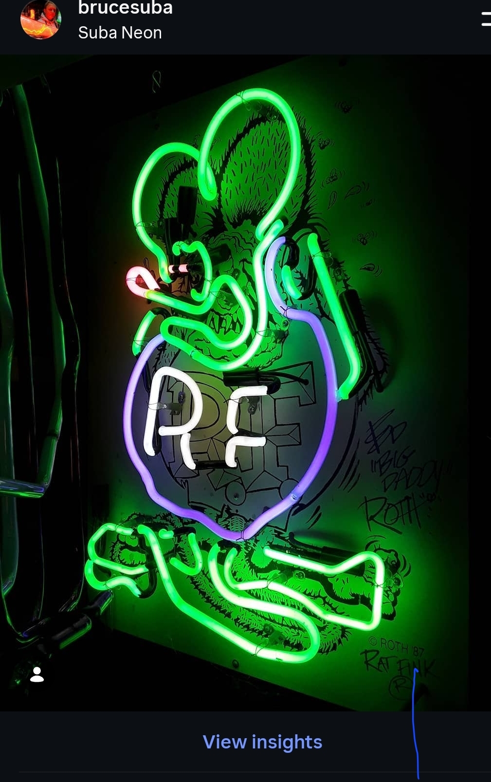 Neon sign of a cartoonish character hugging a bomb with the letters 'RE' on it, glowing in green, purple, and pink.