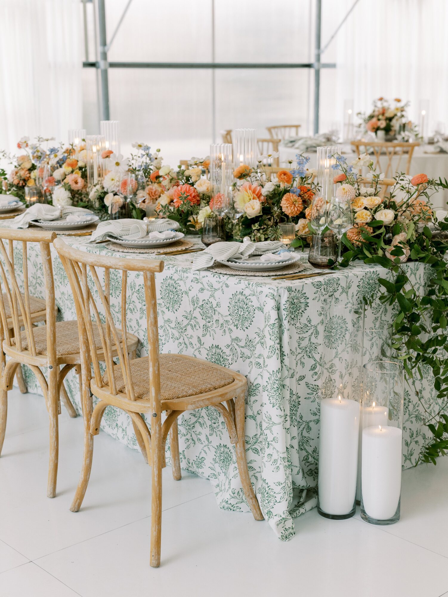 Elegant table setting with floral arrangements, candles, and tableware in a bright, airy venue.