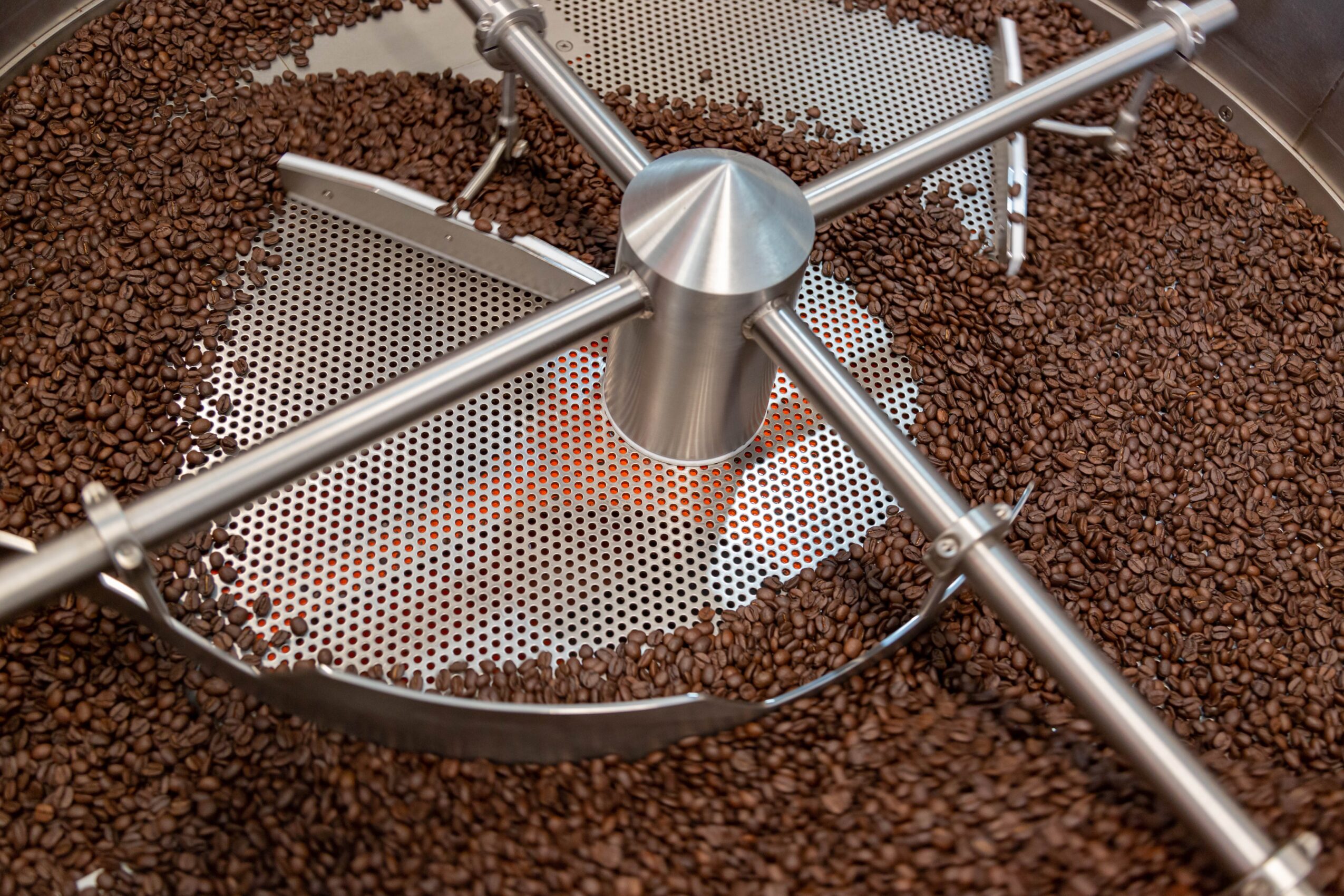 Coffee roasting machine with metal drum and cooling tray filled with roasted coffee beans.