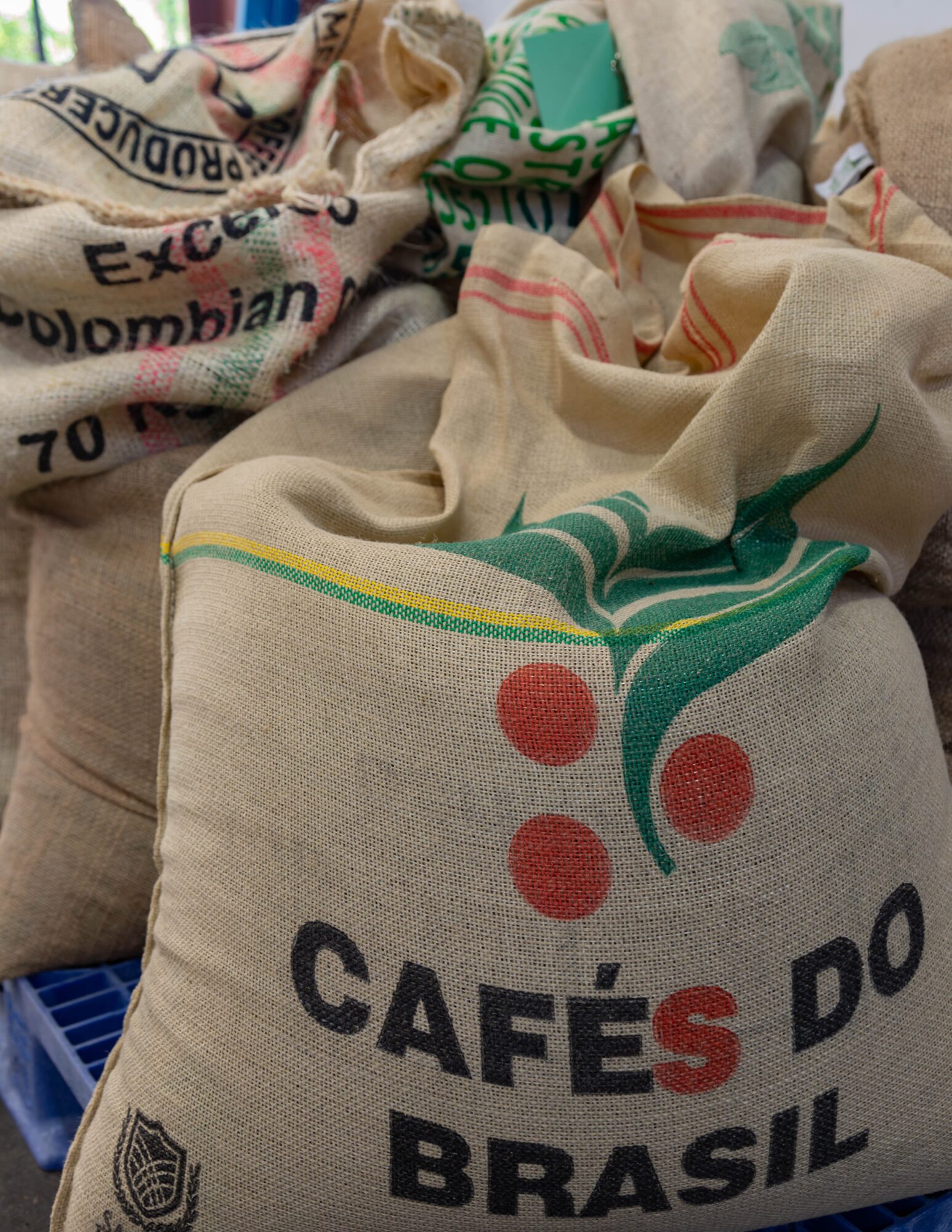Bags of coffee beans with text and colorful designs, stacked on a surface.