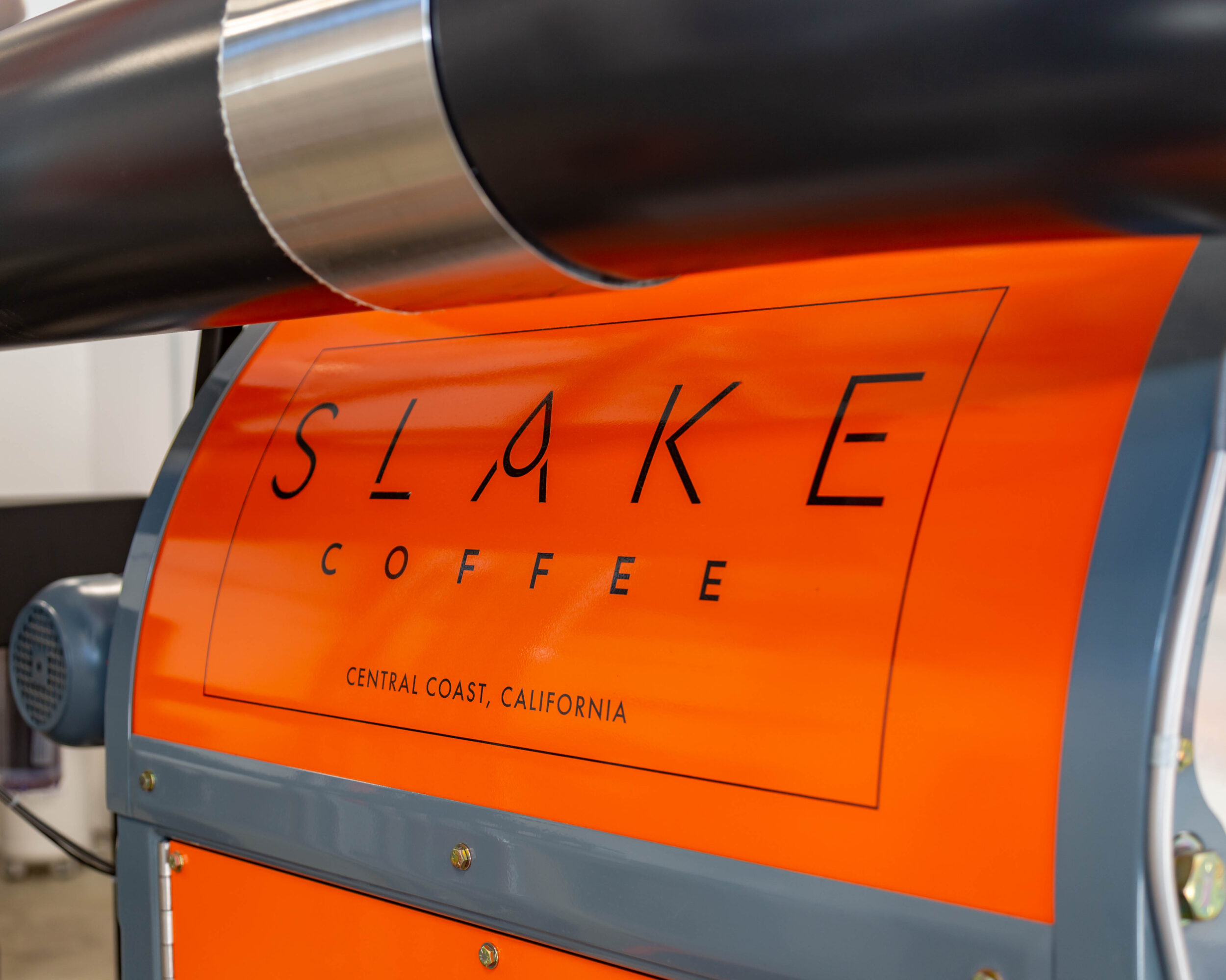 Close-up of a coffee roaster with an orange label reading 'SLIKE COFFEE' and 'Central Coast, California'.