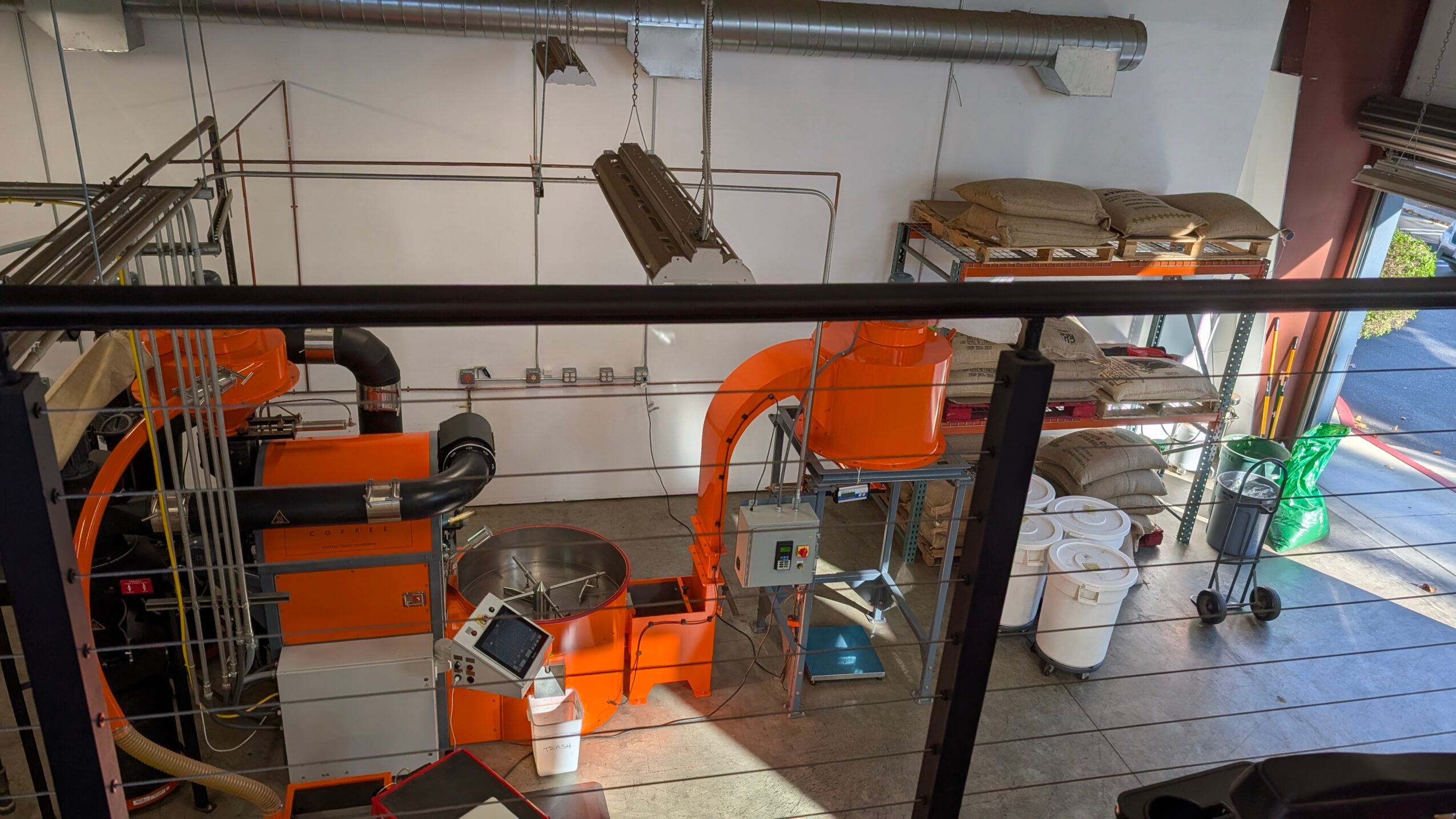 Industrial equipment and machinery in a workshop with shelves and a door in the background.