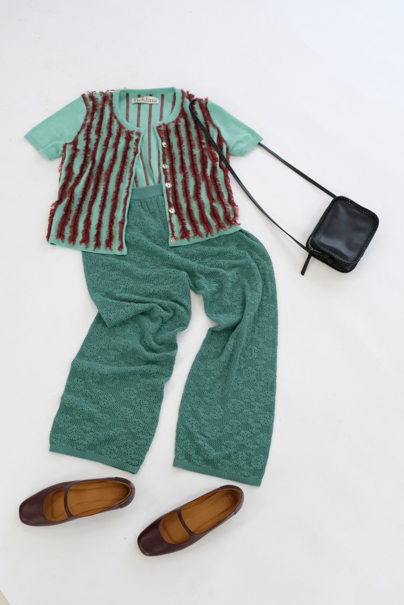 Children's outfit with green pants, striped vest, light blue shirt, brown shoes, and a small black bag, arranged on a white background.
