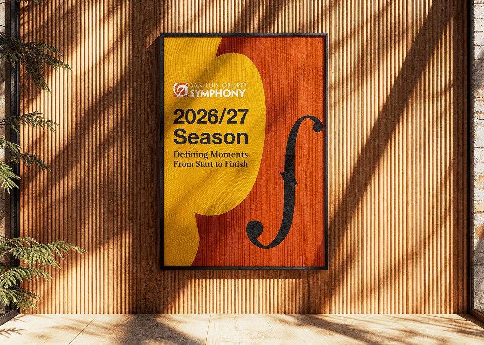 Poster advertising a symphony season with text and a large musical note symbol, mounted on a wooden wall with sunlight and shadows.