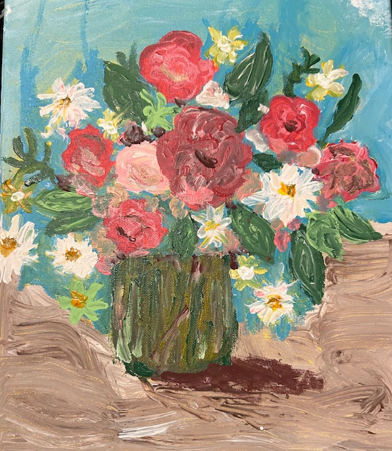 A colorful bouquet of pink, red, and white flowers in a green vase on a wooden surface, with a blue background.