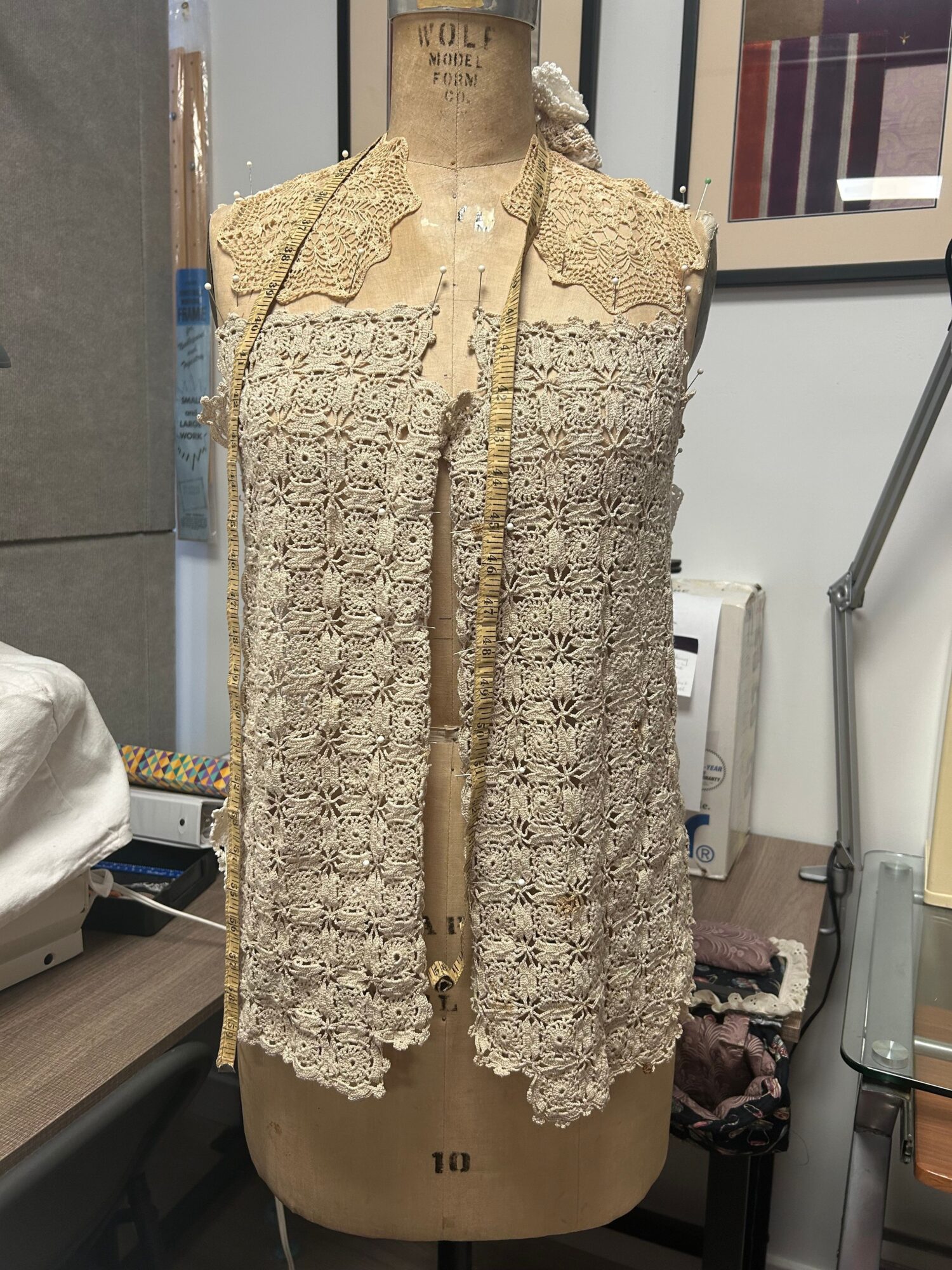 Beige lace dress with floral pattern and long sleeves displayed on a mannequin in a room.