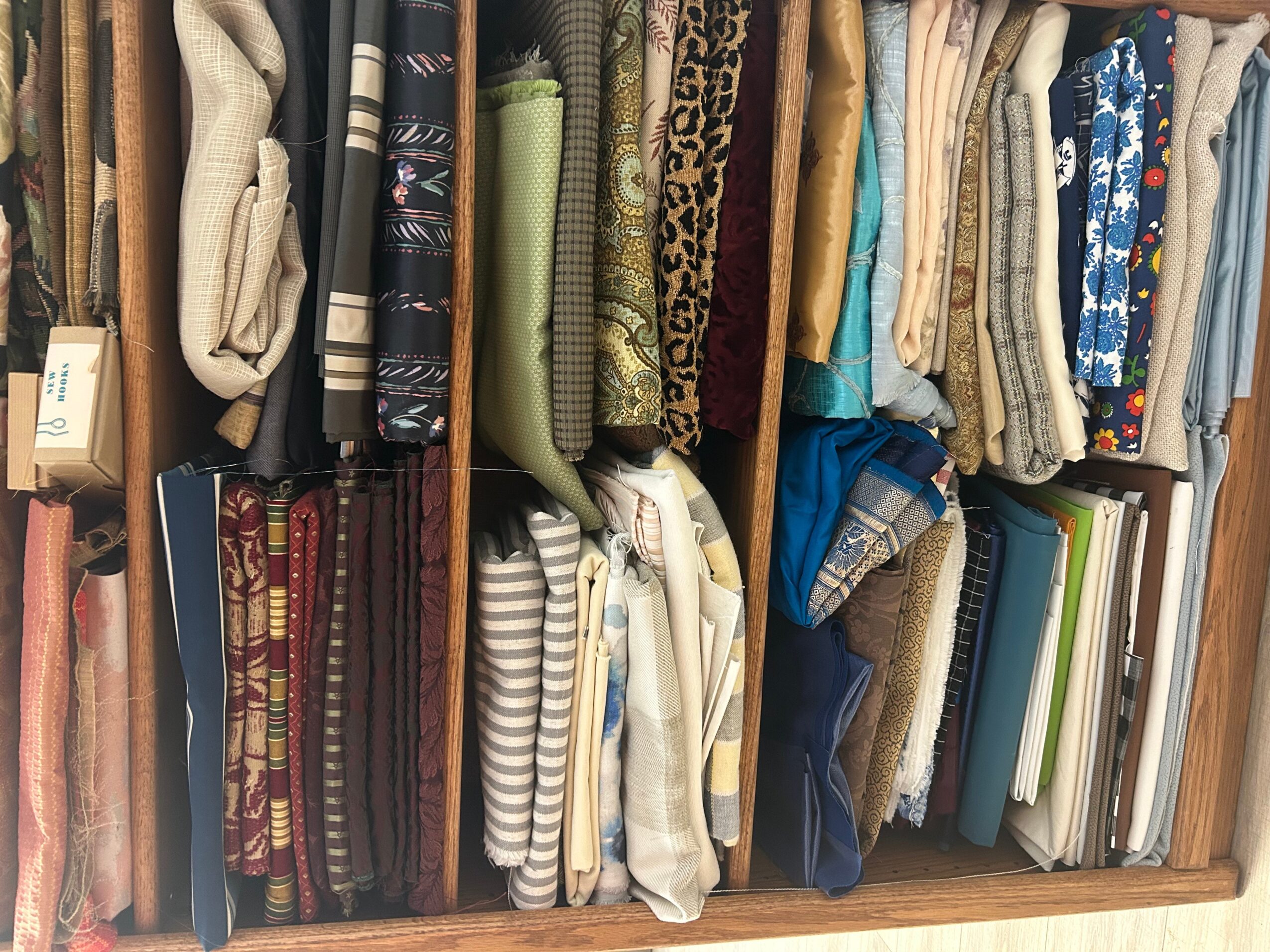 Closet shelf with folded clothes, books, and accessories arranged vertically.