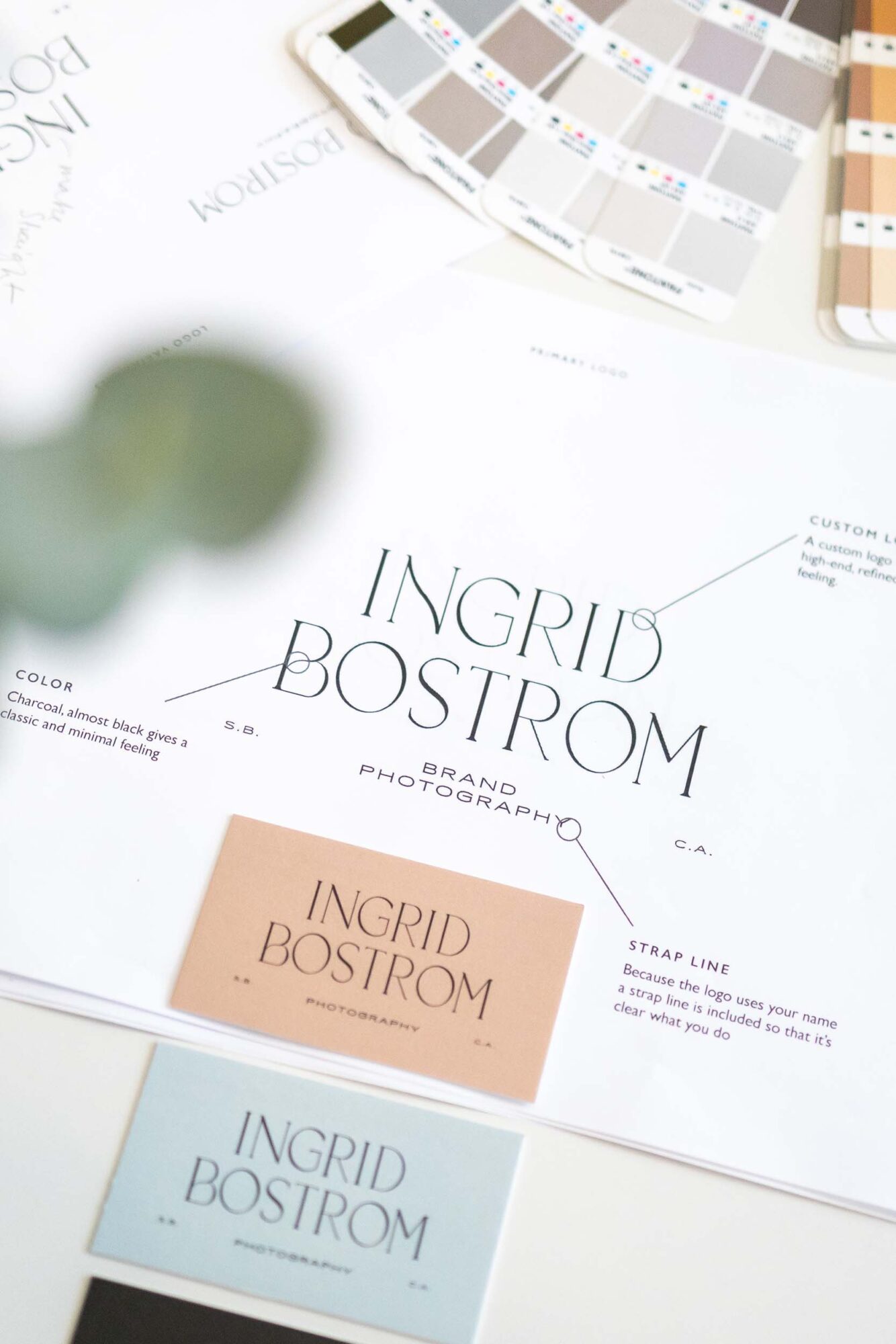 Design catalog with color swatches and a page showing the name Ingrid Bostrom, with a blurred green object in the foreground.