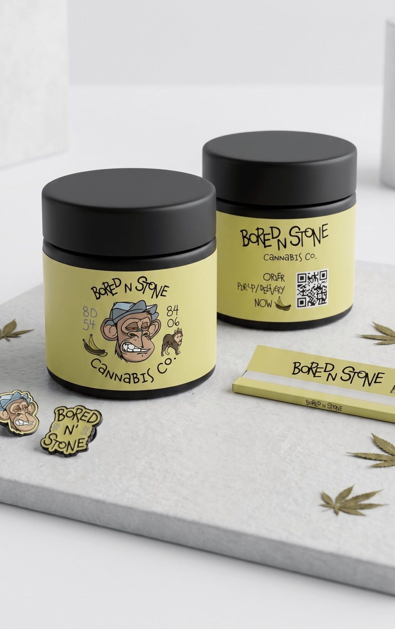 Two yellow containers with black lids labeled 'Bored & Stoned Cannabis' and a cartoon face, on a white surface with cannabis leaves.