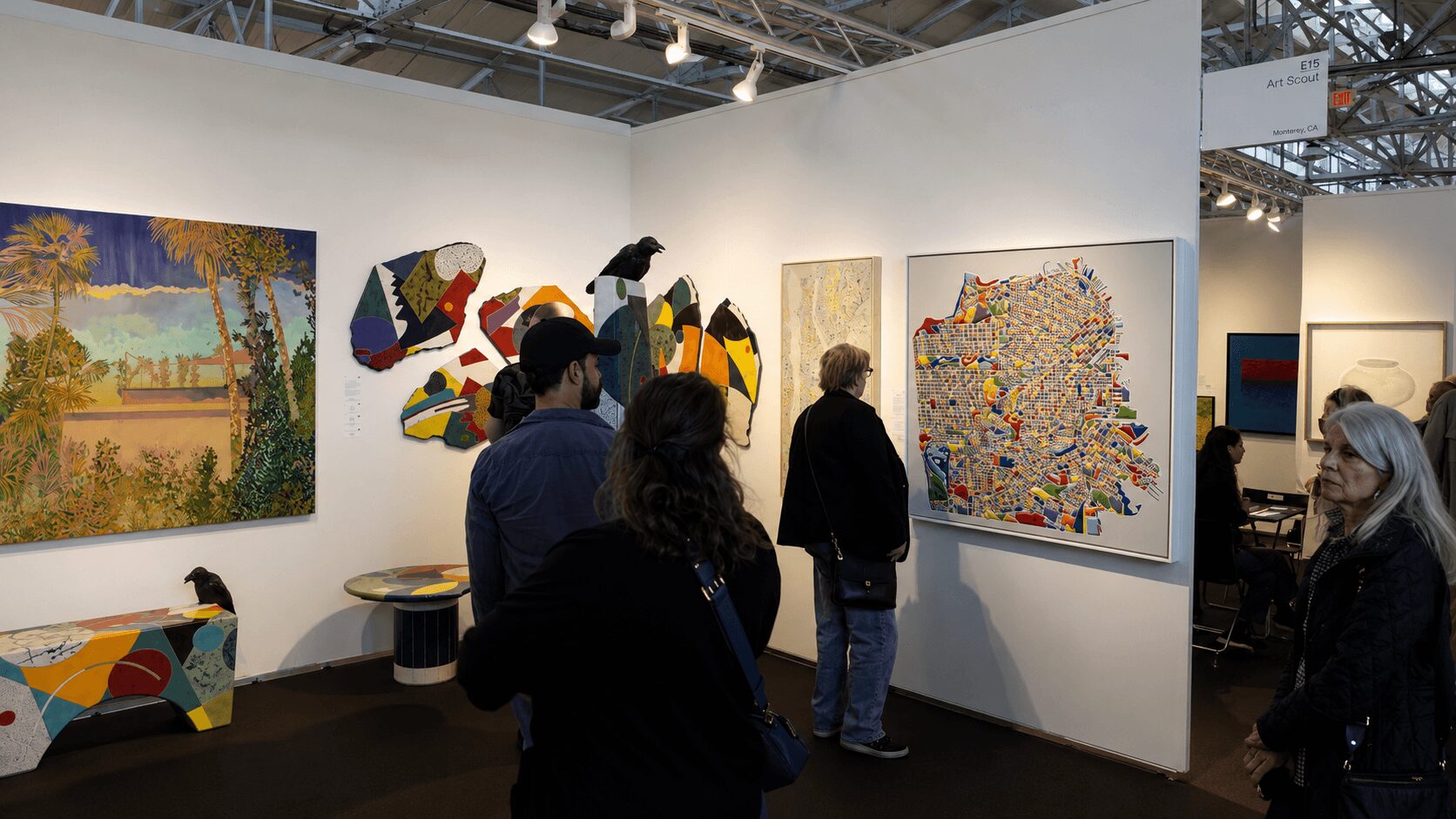 Group of people viewing colorful artwork in an art gallery with white walls.