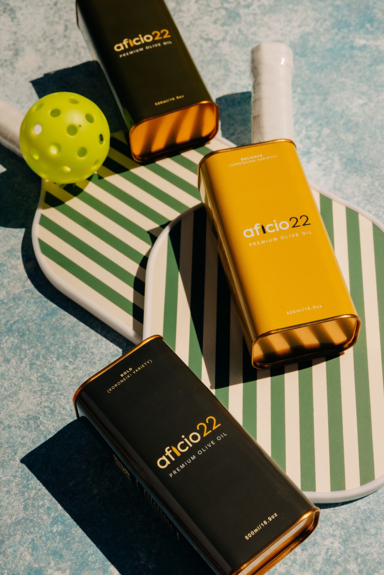 Yellow bottle and black box with 'aficio 22' text, green ball, and striped surface, with a textured background.