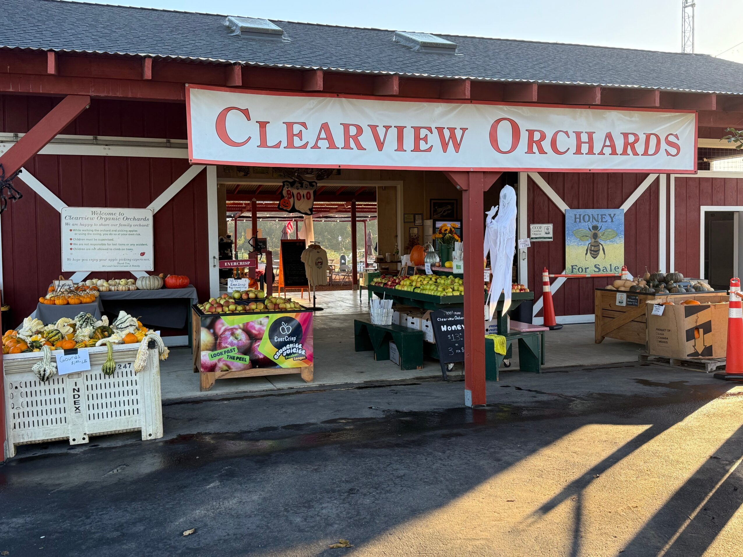 Entrance of Clearview Orchards with fruit displays and a sign above, sunny day, outdoor market scene.