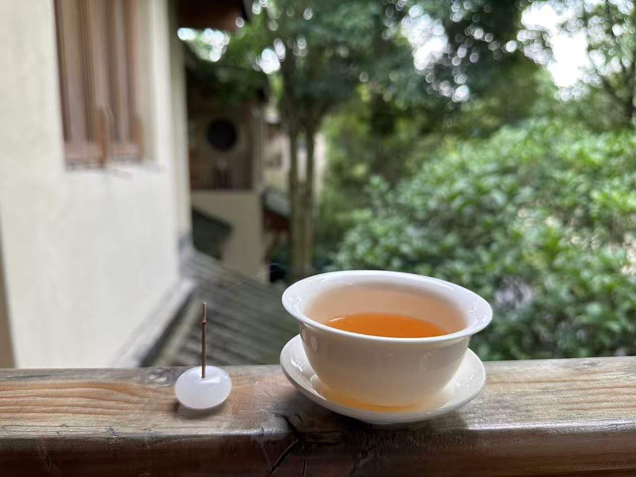 Tea cup on wooden railing with outdoor greenery in background