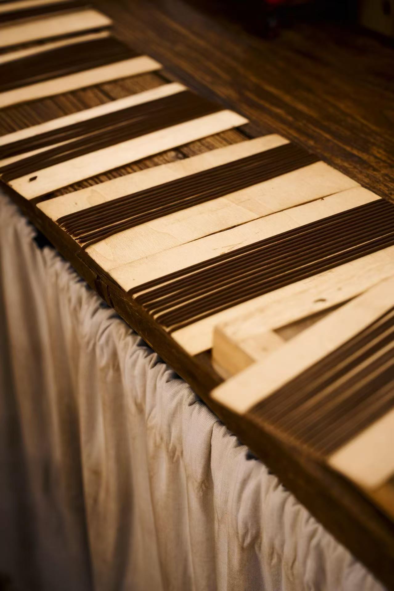 Piano keys arranged on a table with black and white keys, some keys are missing or damaged, viewed from above.