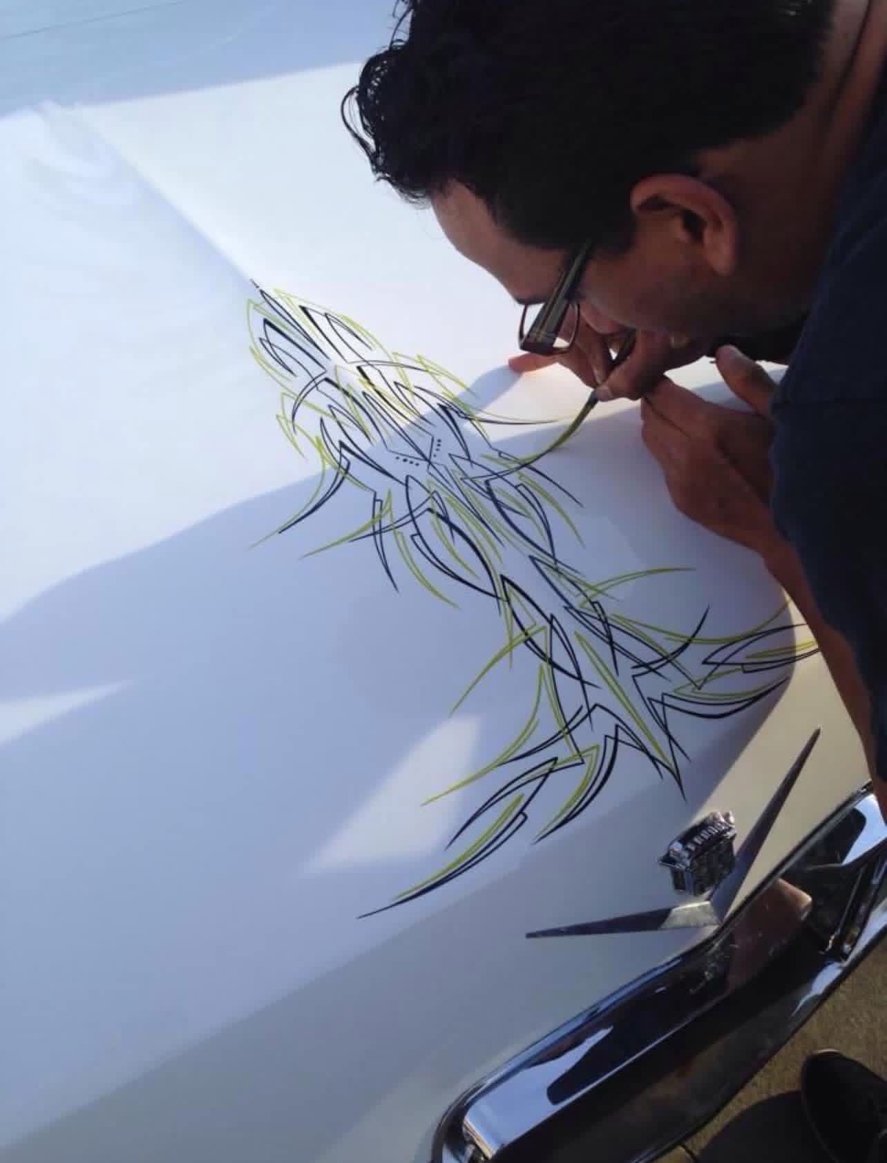 Person drawing with a marker on large white paper, creating a detailed design with lines and shapes.
