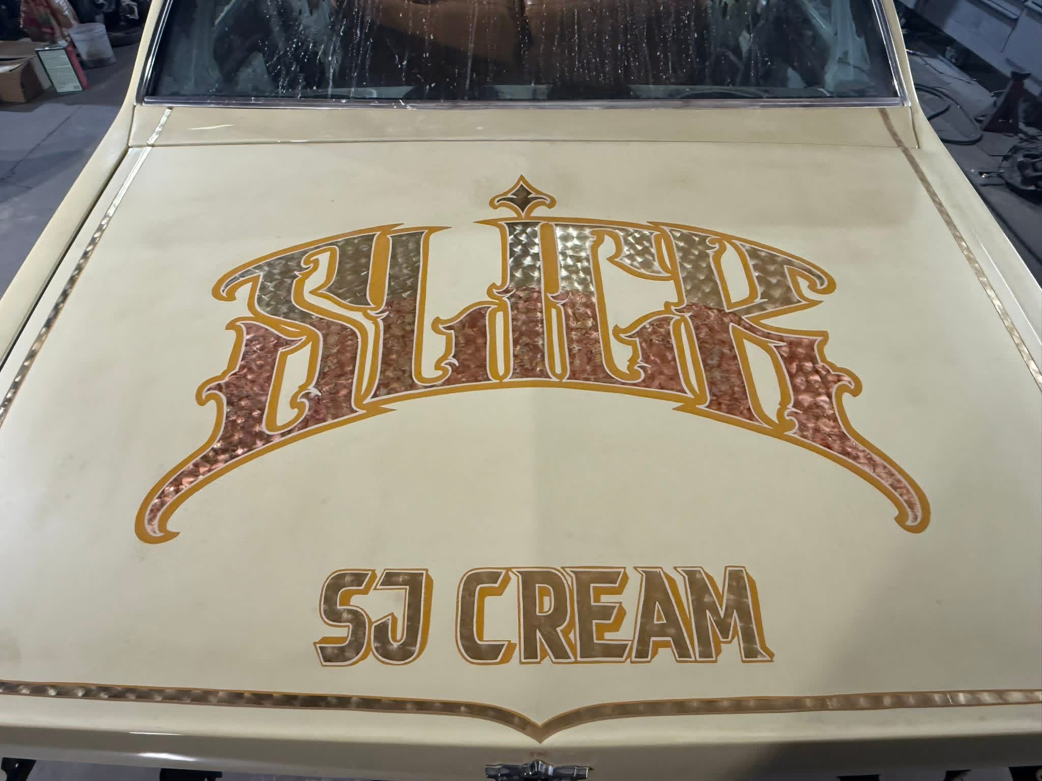 Close-up of a vintage vehicle hood with a logo reading 'Flick' and 'SJ CREAM' in stylized lettering.