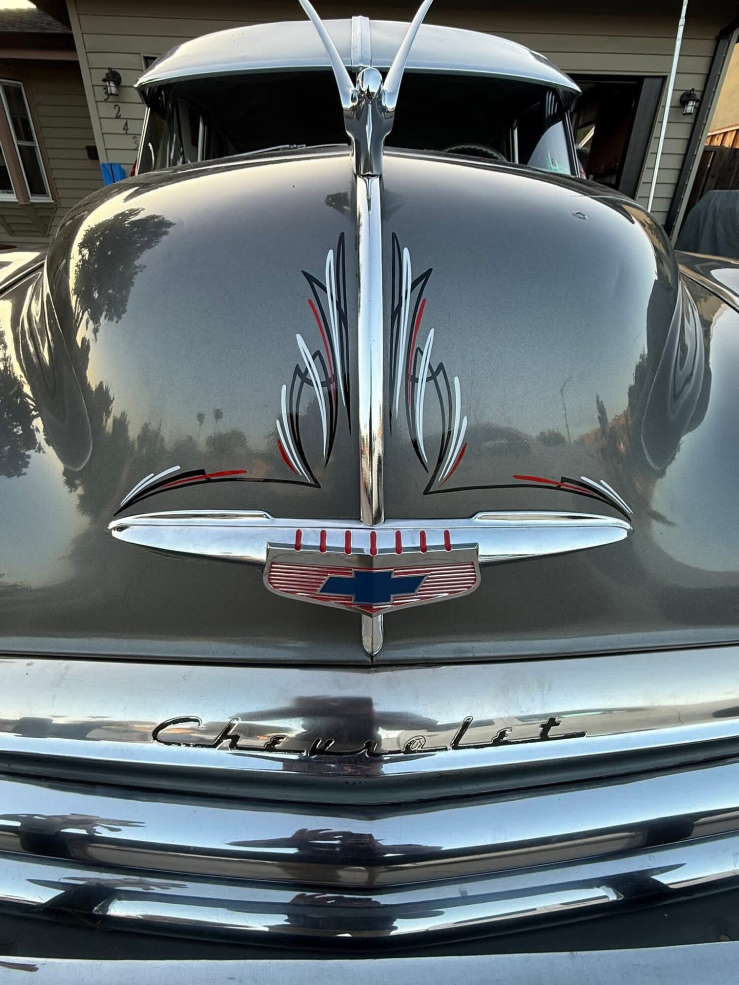 Front view of a vintage car with chrome details and a Chevrolet emblem, parked outdoors with buildings in the background.