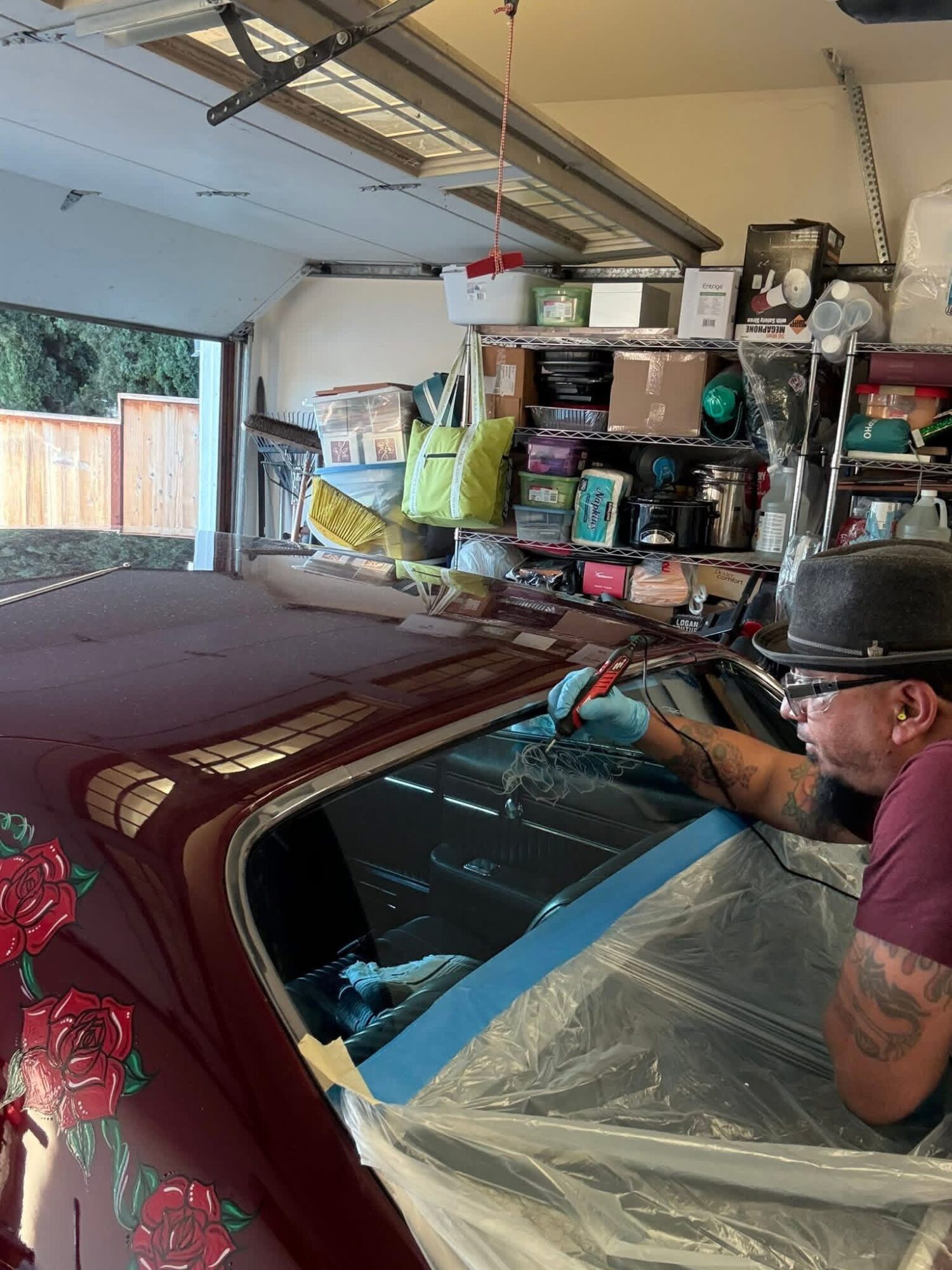 Person working on a car in a garage, with shelves and storage boxes in the background.