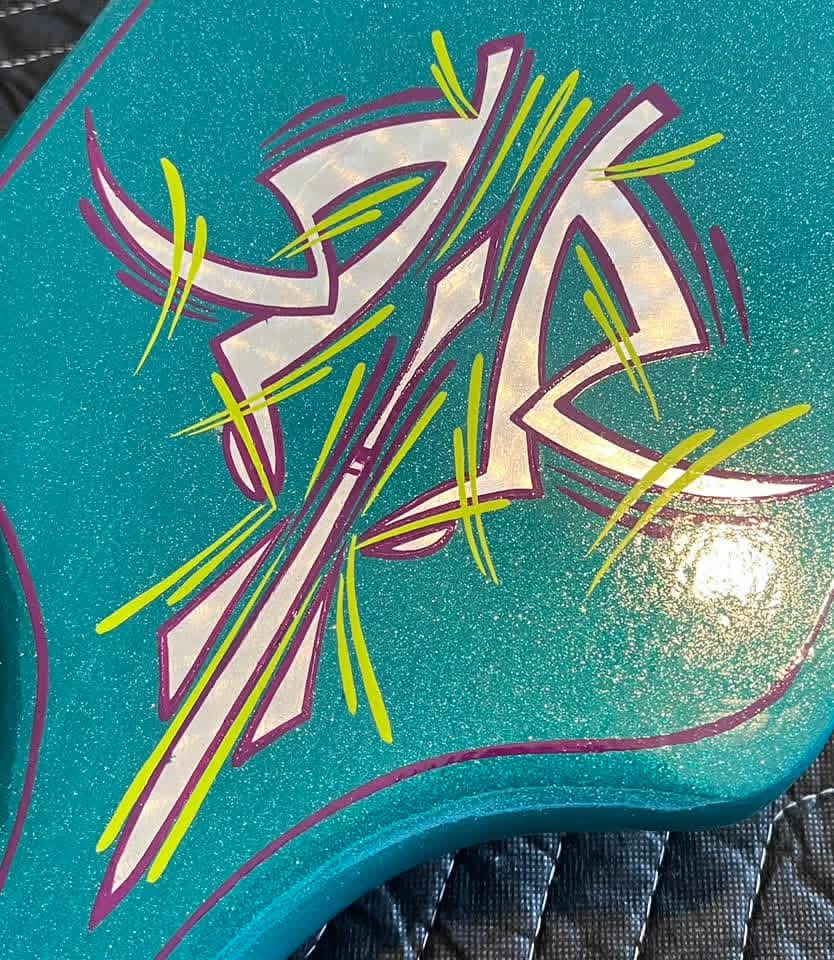 Colorful graffiti with abstract shapes and lines on a teal background.