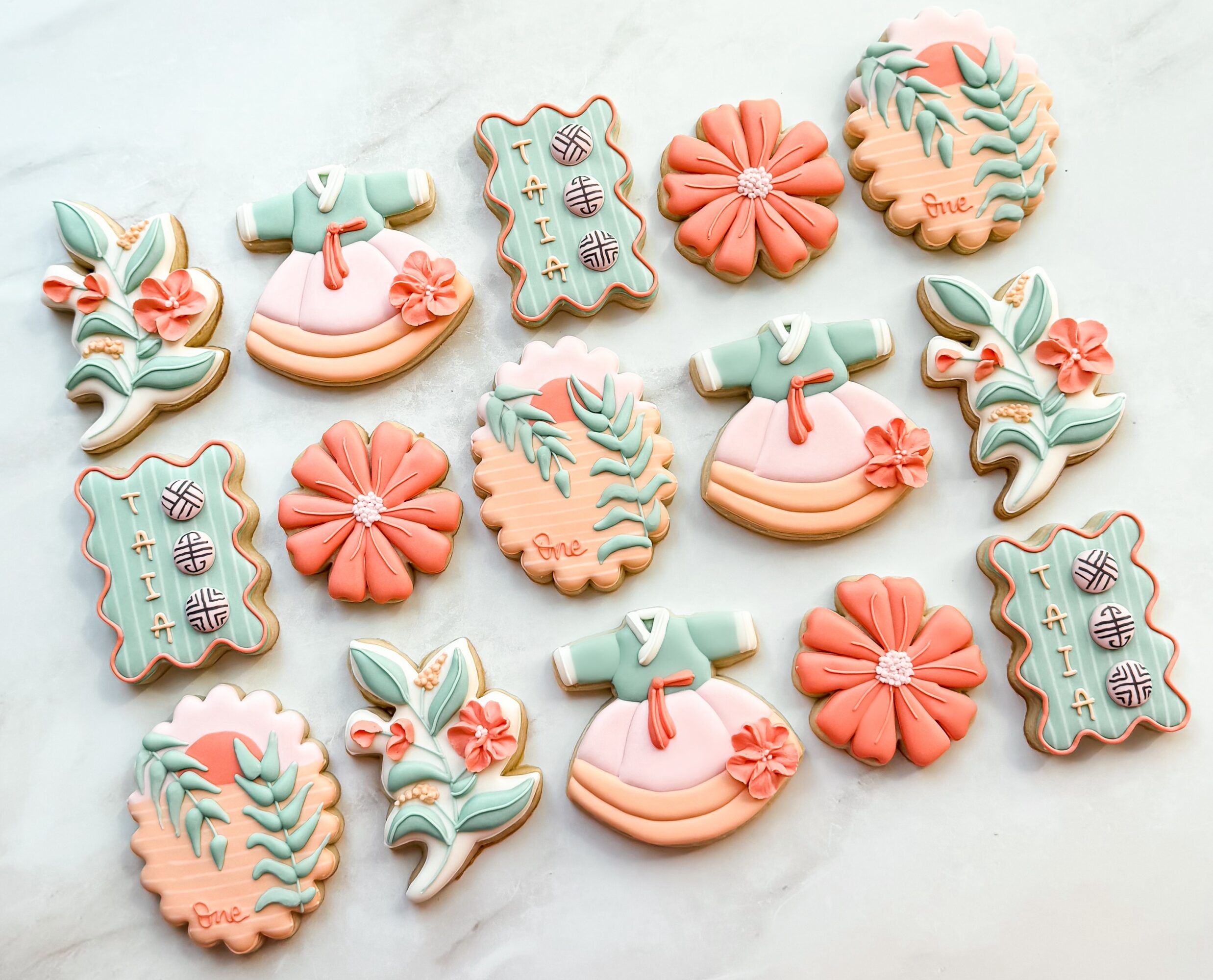 Assorted decorated cookies with floral, leaf, and gift box designs in pastel colors on a light background.