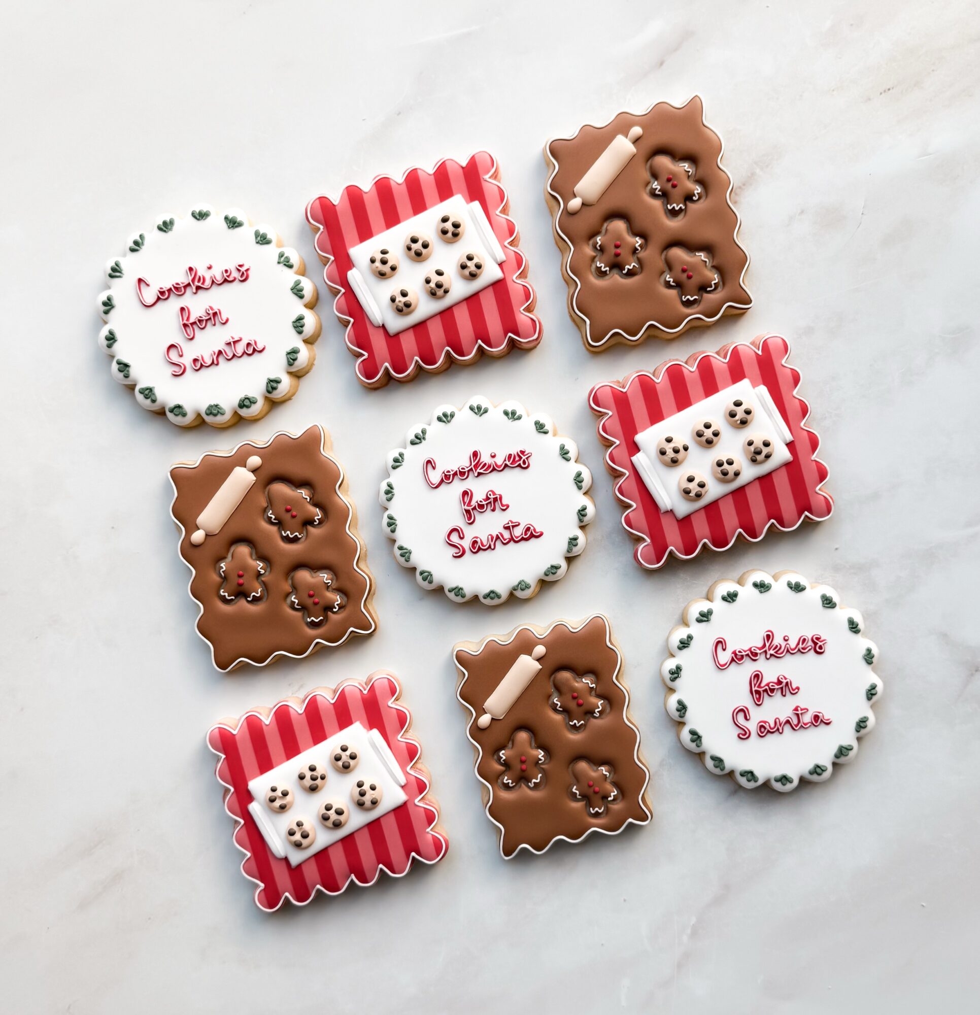 Assorted decorated cookies with Christmas themes on a white surface, including cookies with 'Cookies from Santa' text and gingerbread shapes.