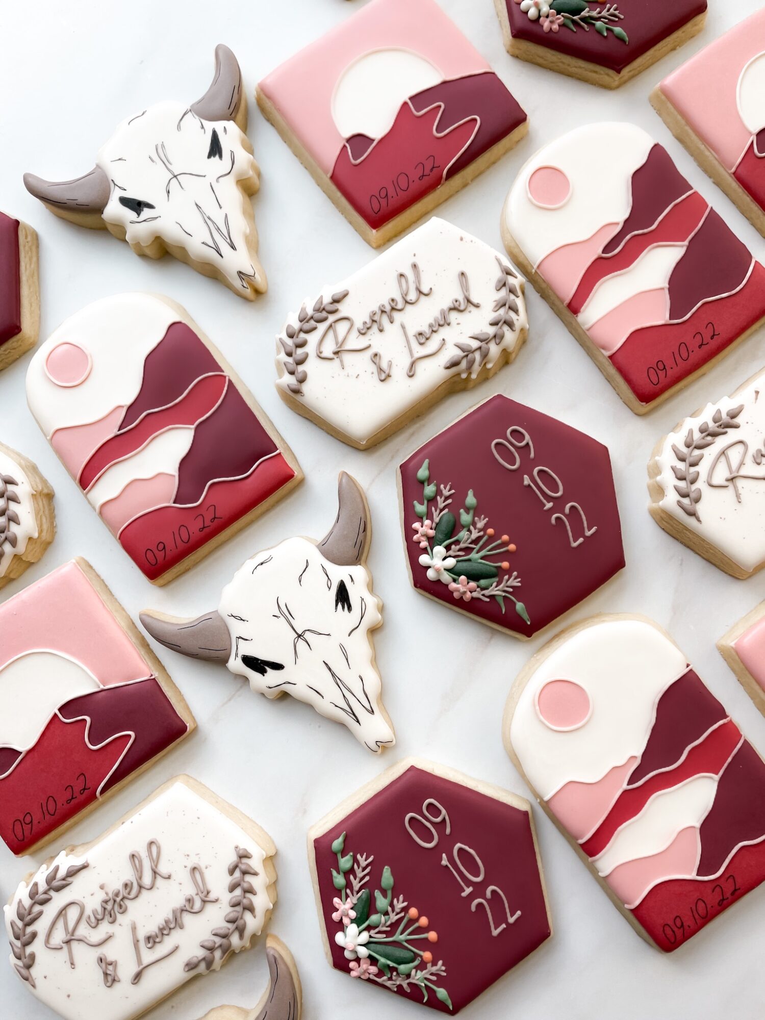 Decorative cookies with Christmas themes, including a reindeer skull, holly, and abstract patterns, arranged on a white surface.