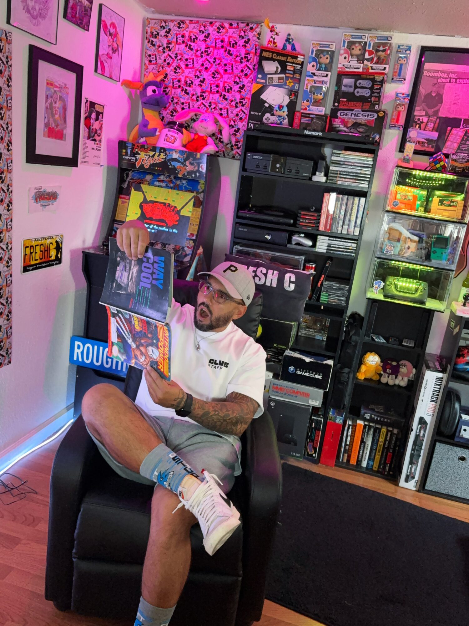 Person sitting in a black chair reading a magazine in a colorful room with shelves, toys, and artwork.