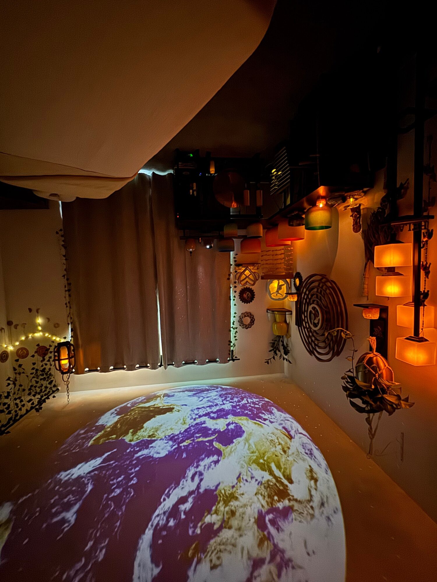 Room with Earth projection on ceiling, curtains, candles, and decorative items, creating a cozy atmosphere.